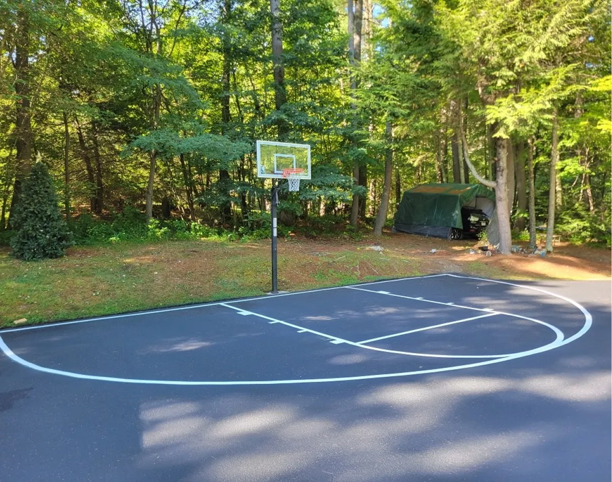 Freshly paved residential basketball court with smooth asphalt surface and clear line striping